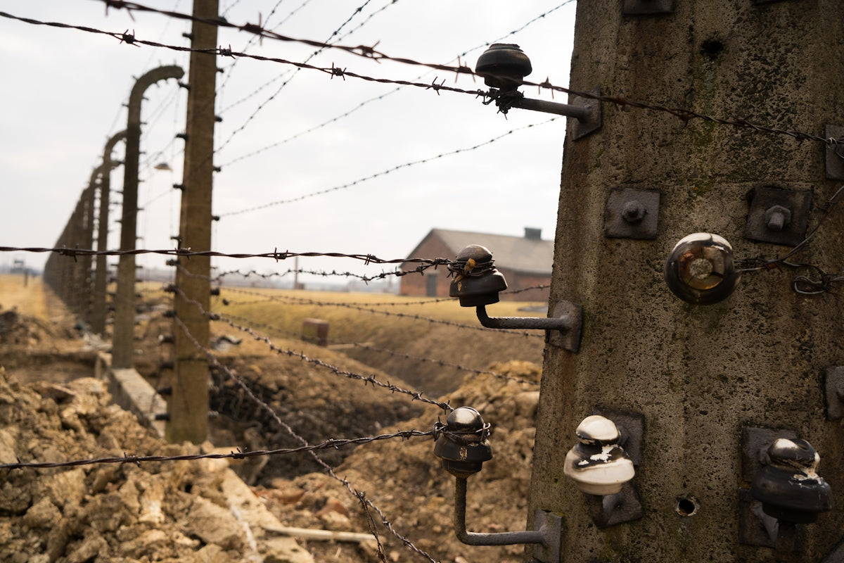 a barbed wire fence with a house in the background