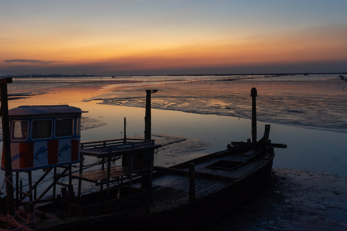 a boat sitting on top of a beach next to a body of water