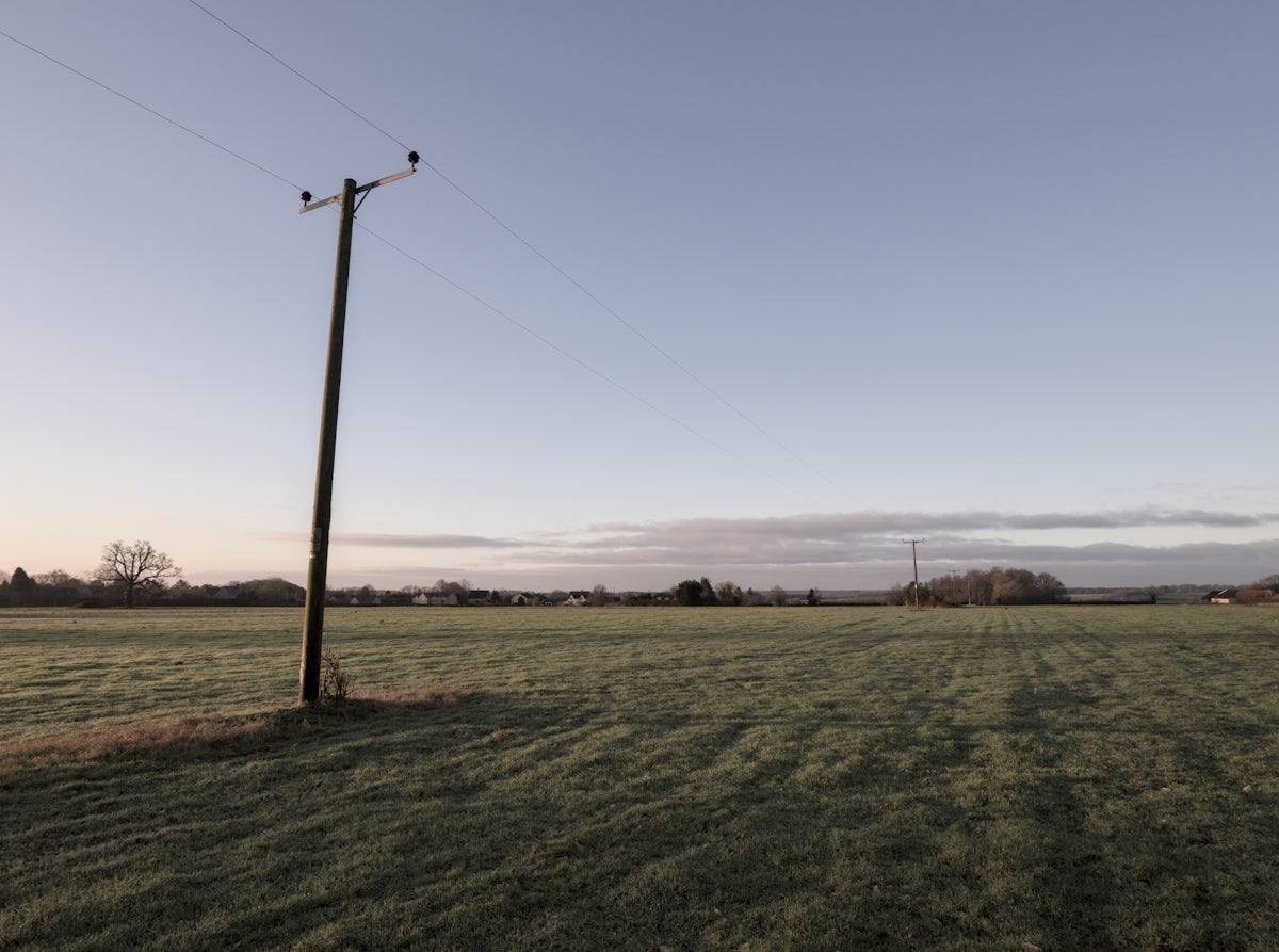 a field with a telephone pole in the middle of it