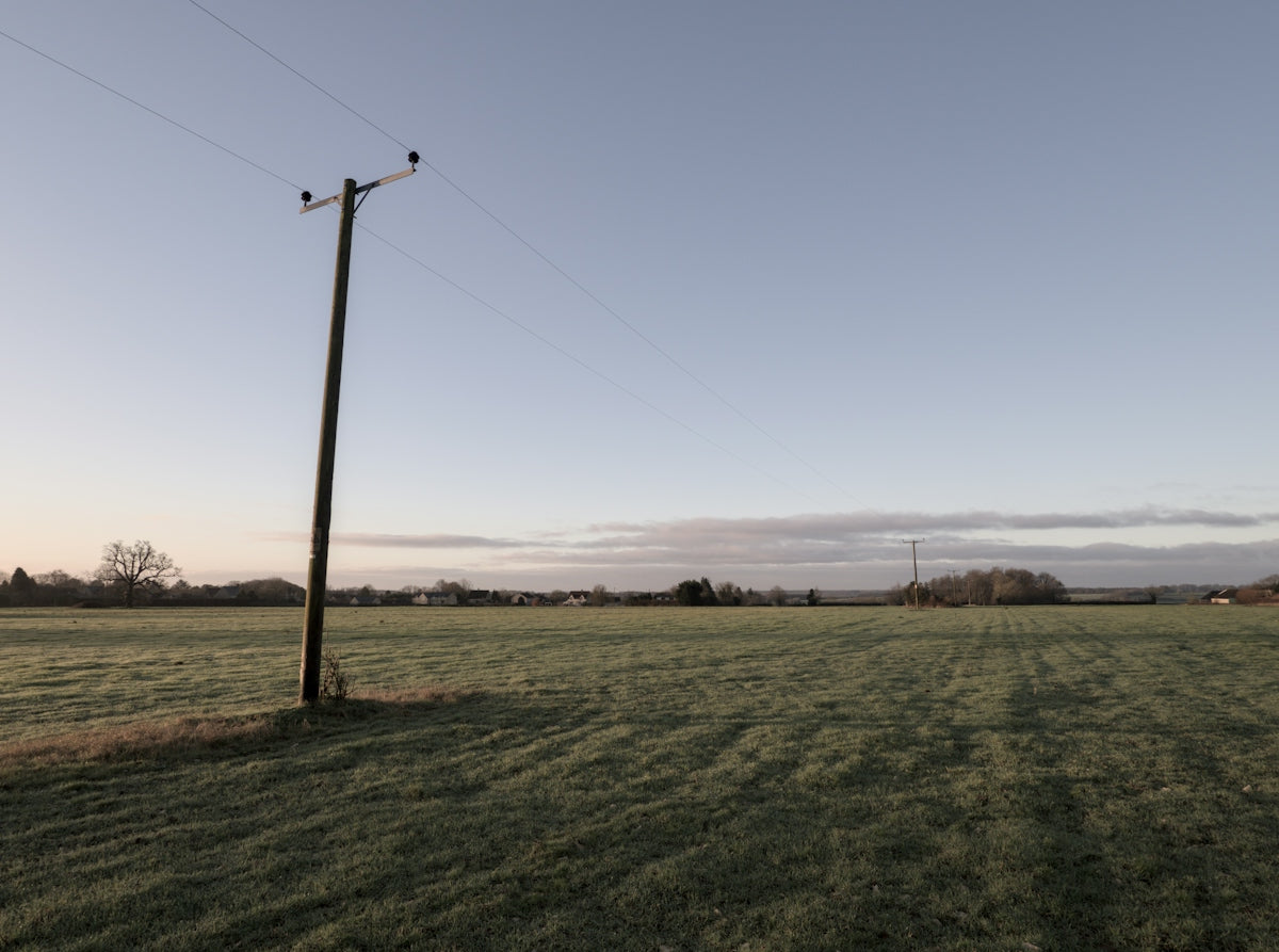 a field with a telephone pole in the middle of it
