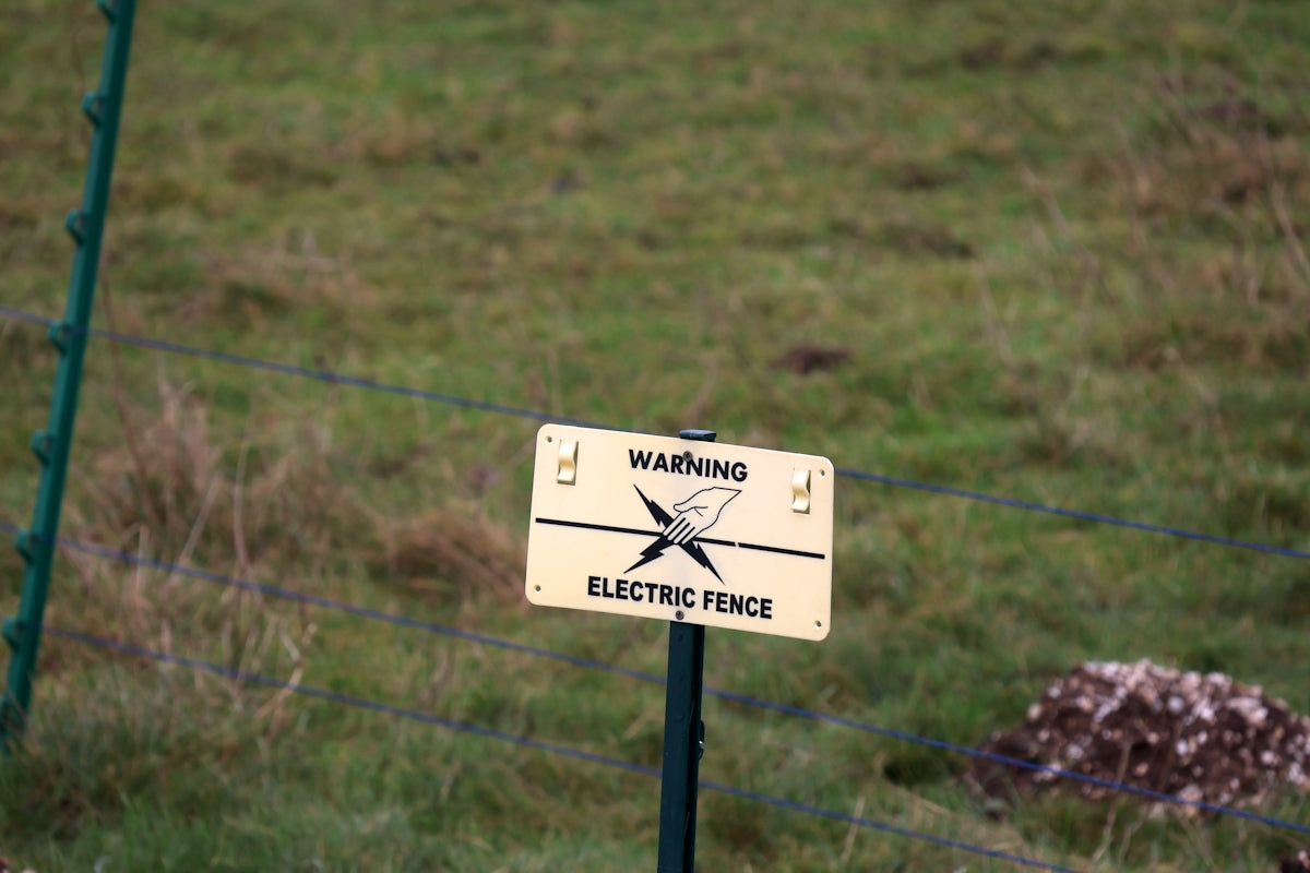 A sign on a post in front of a fence
