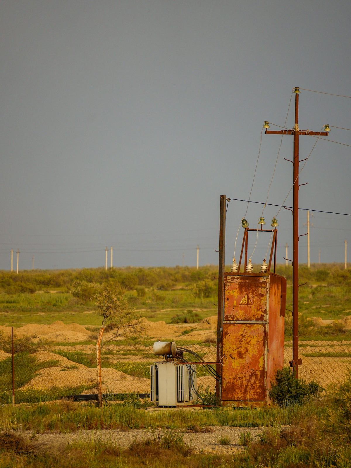 An old, rusty power substation in the field.