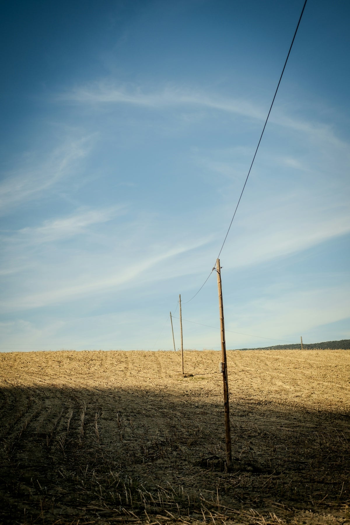 Wooden poles with wire stretch across dry field