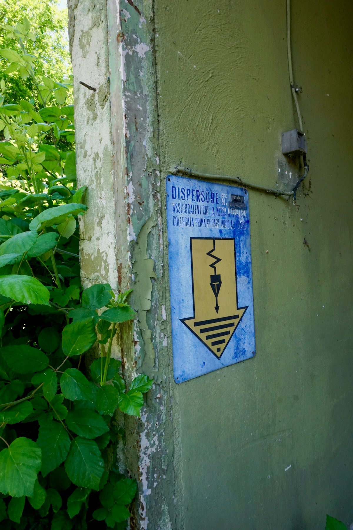 A blue sign with electrical warning symbols on a wall.