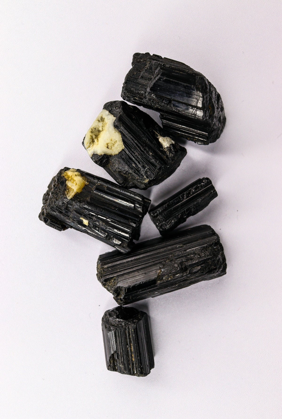 Several rough black tourmaline crystals on a white background
